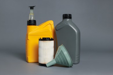 Photo of Motor oil in plastic canisters, filter and funnel on grey background