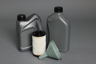 Photo of Motor oil in plastic canisters, filter and funnel on grey background
