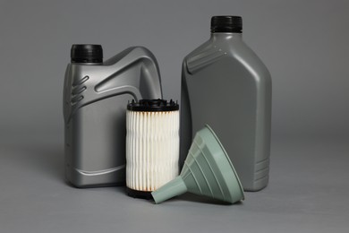 Photo of Motor oil in plastic canisters, filter and funnel on grey background