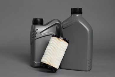 Photo of Motor oil in plastic canisters and filter on grey background