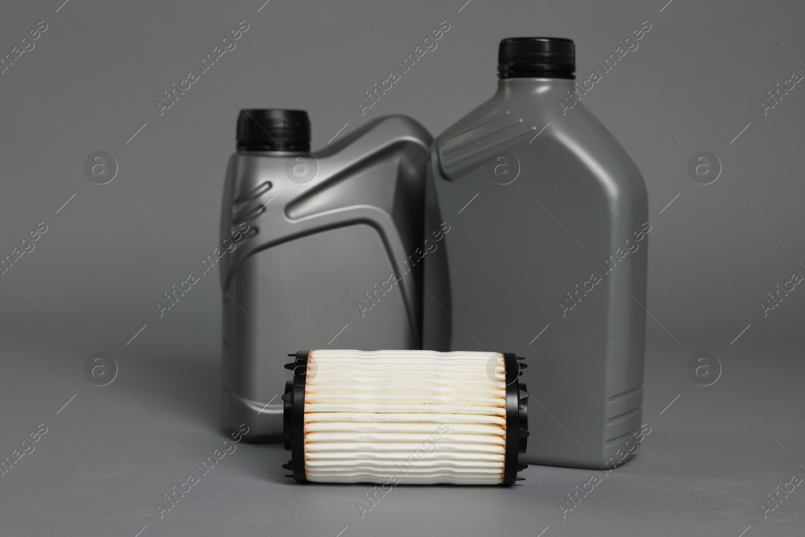 Motor oil in plastic canisters and filter on grey background Photo of Motor oil in plastic canisters and filter on grey background