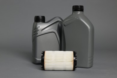 Photo of Motor oil in plastic canisters and filter on grey background