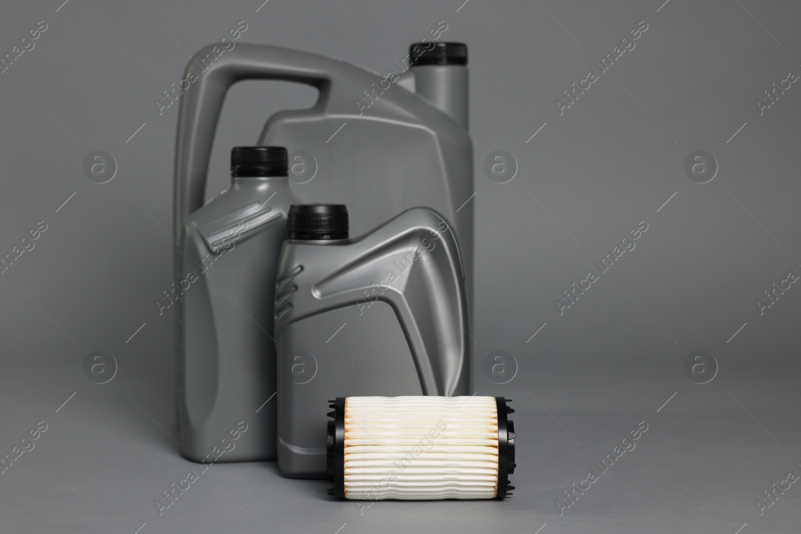 Motor oil in plastic canisters and filter on grey background, space for text Photo of Motor oil in plastic canisters and filter on grey background, space for text