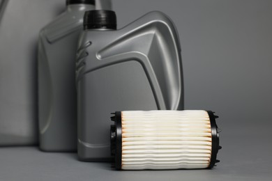 Photo of Motor oil in plastic canisters and filter on grey background, closeup