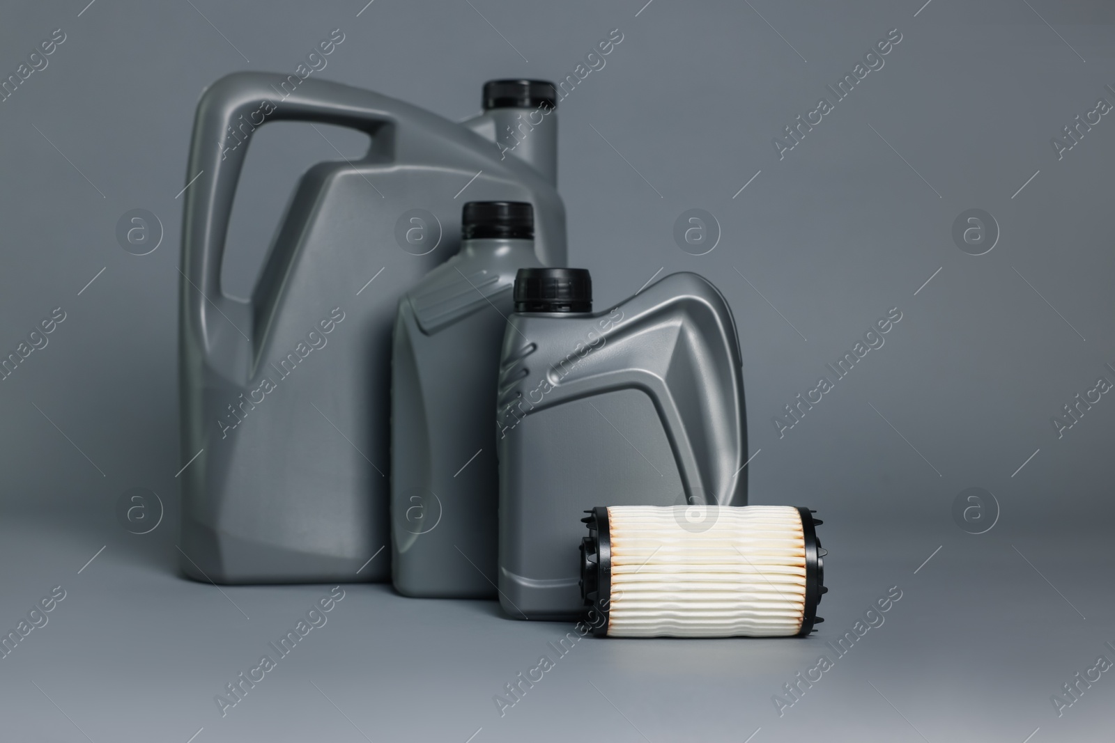 Motor oil in plastic canisters and filter on grey background Photo of Motor oil in plastic canisters and filter on grey background