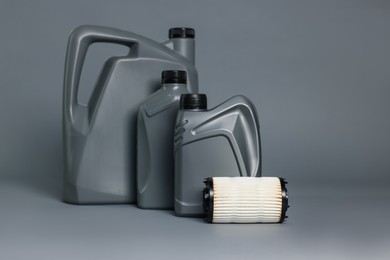 Photo of Motor oil in plastic canisters and filter on grey background