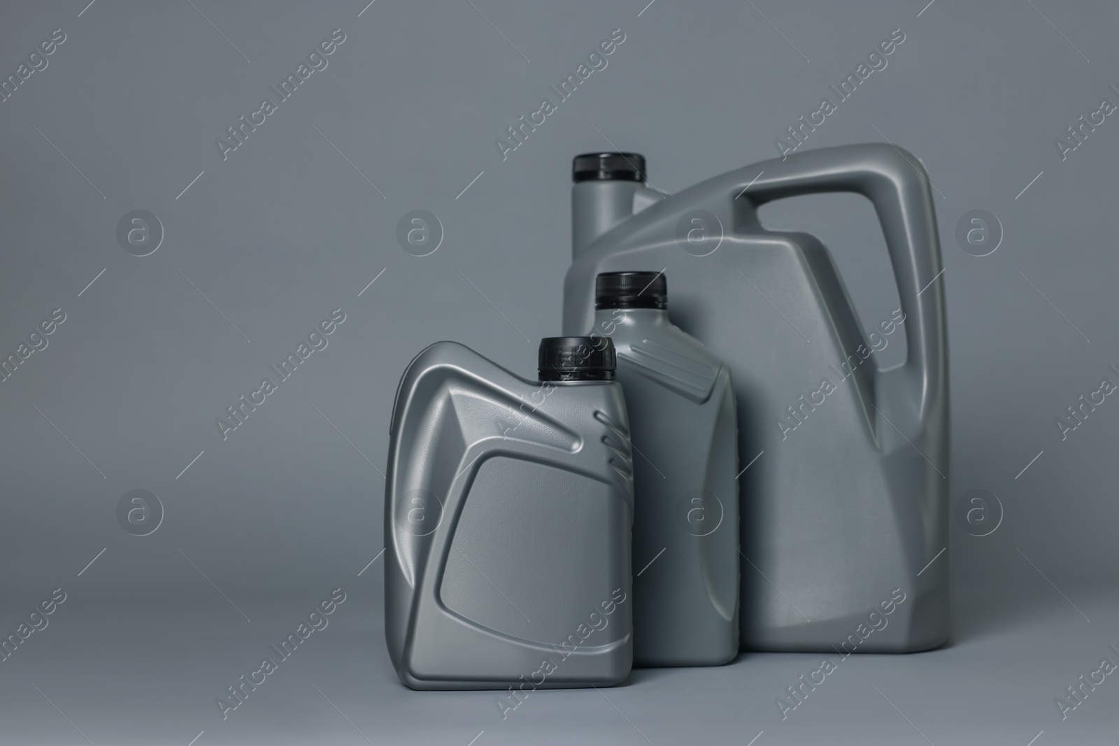 Motor oil in plastic canisters on grey background, space for text Photo of Motor oil in plastic canisters on grey background, space for text
