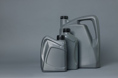 Photo of Motor oil in plastic canisters on grey background, space for text