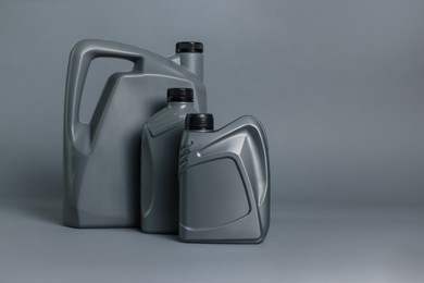 Photo of Motor oil in plastic canisters on grey background, space for text