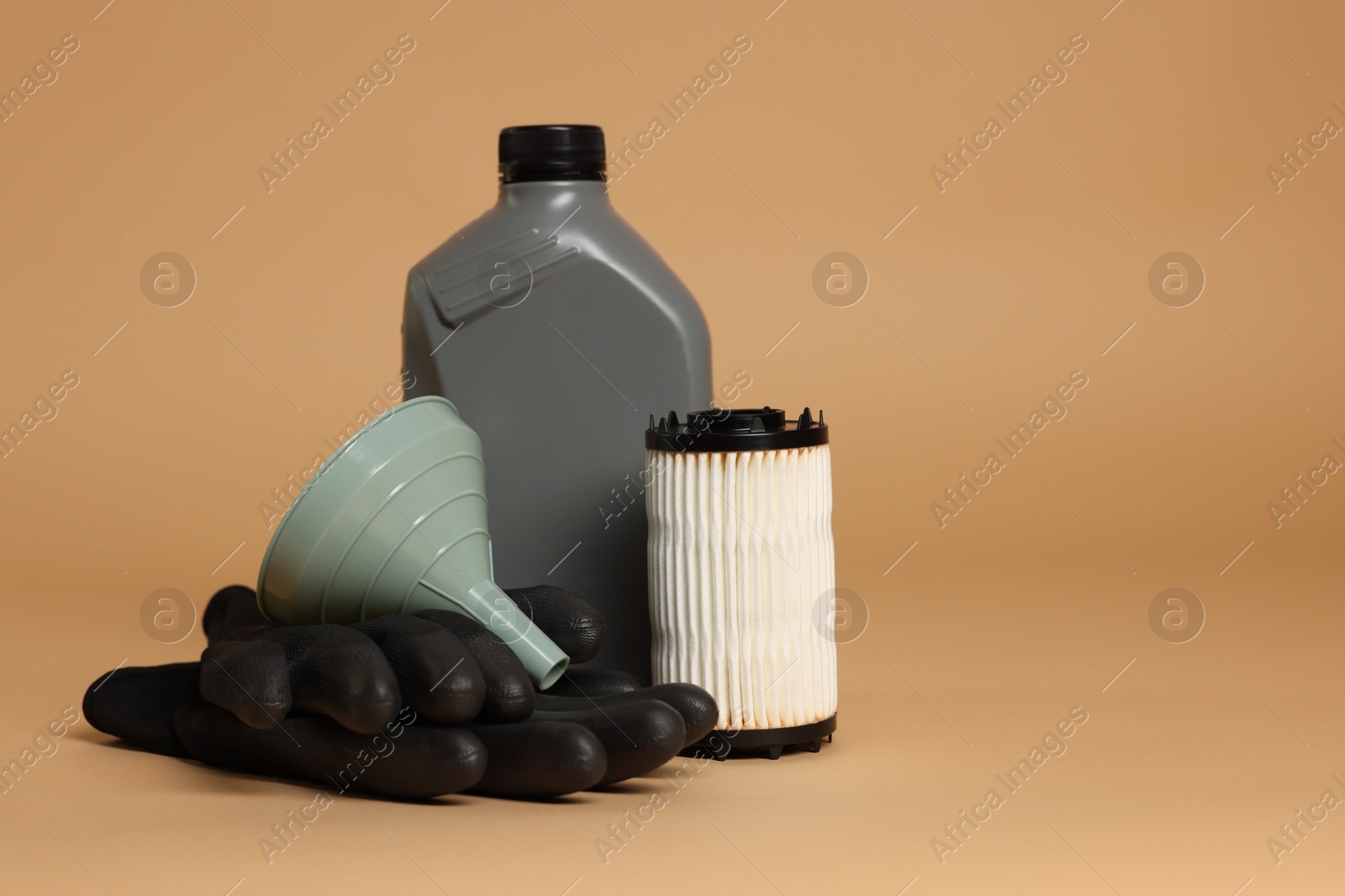 Motor oil in plastic canister, filter, gloves and funnel on beige background, space for text Photo of Motor oil in plastic canister, filter, gloves and funnel on beige background, space for text
