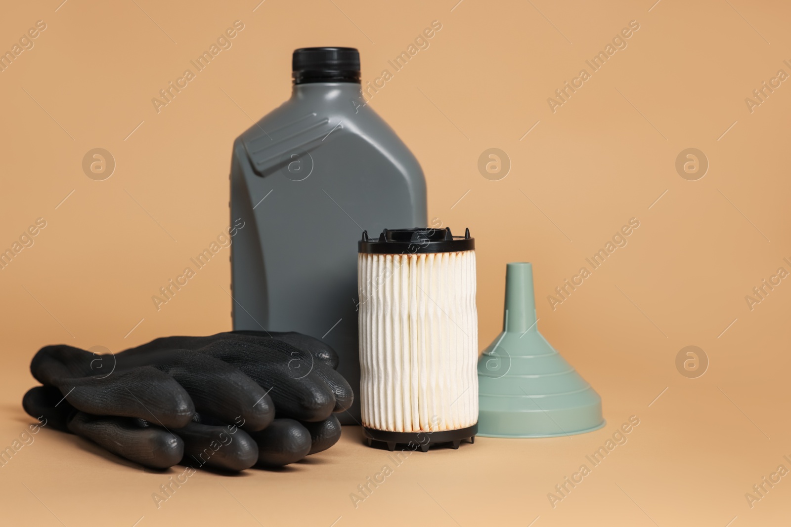 Motor oil in plastic canister, filter, gloves and funnel on beige background Photo of Motor oil in plastic canister, filter, gloves and funnel on beige background