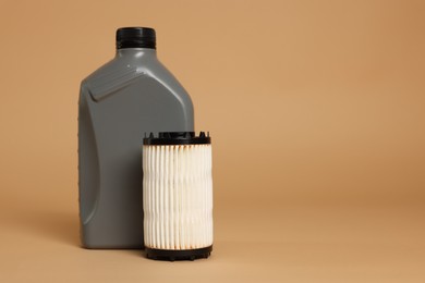 Photo of Motor oil in plastic canister and filter on beige background, space for text