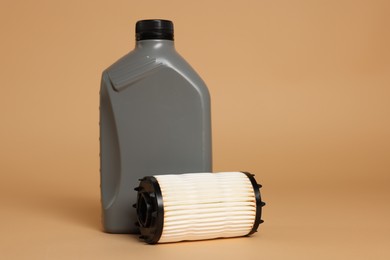 Photo of Motor oil in plastic canister and filter on beige background, space for text