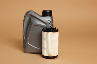 Photo of Motor oil in plastic canister and filter on beige background, space for text