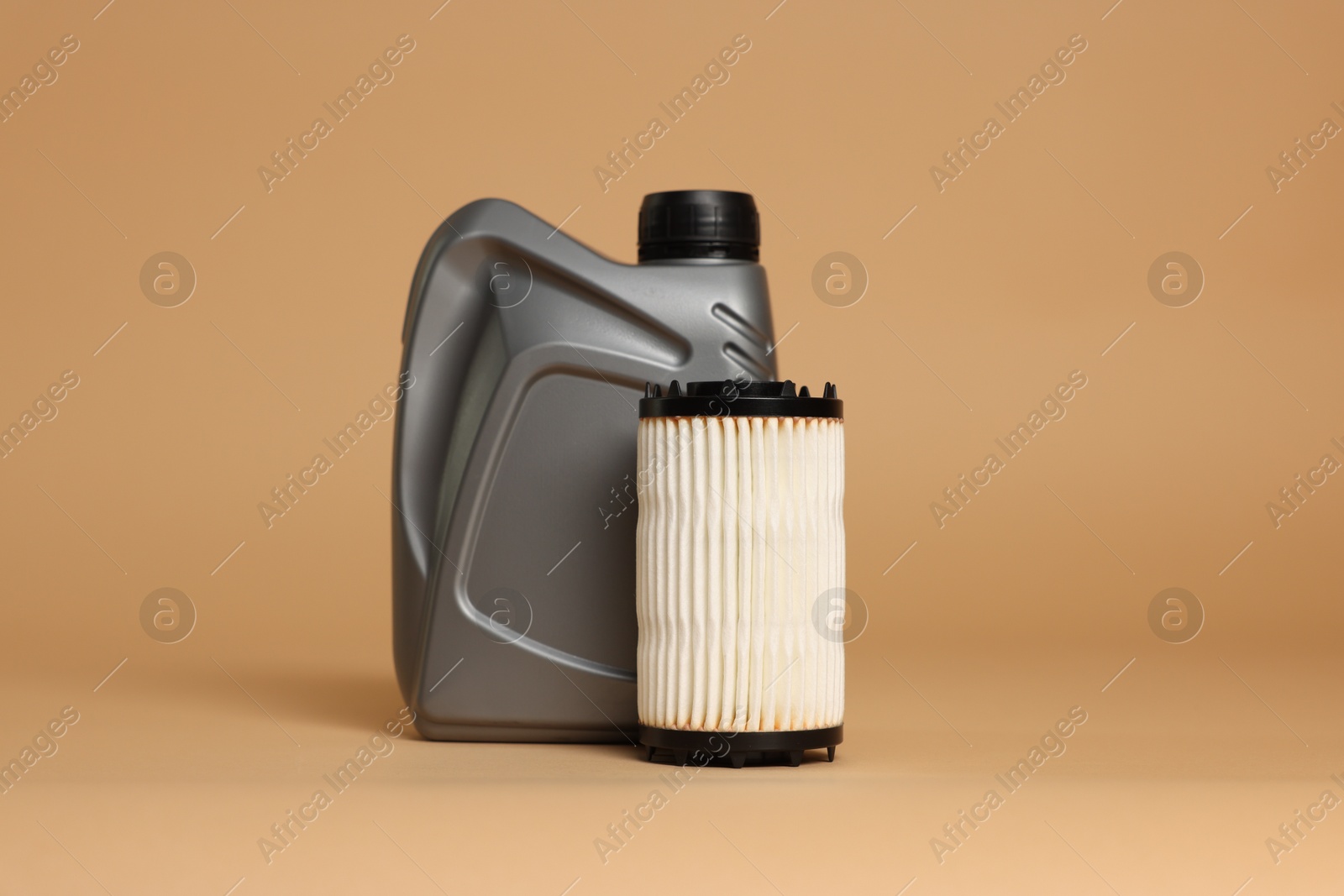 Motor oil in plastic canister and filter on beige background Photo of Motor oil in plastic canister and filter on beige background