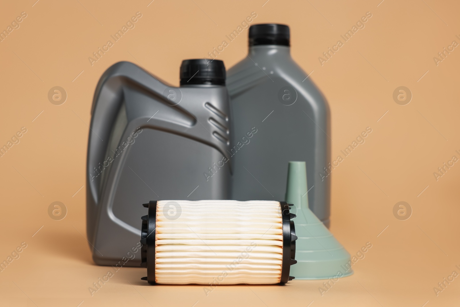 Motor oil in plastic canisters, filter and funnel on beige background Photo of Motor oil in plastic canisters, filter and funnel on beige background