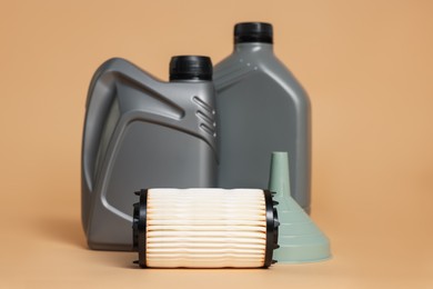 Photo of Motor oil in plastic canisters, filter and funnel on beige background