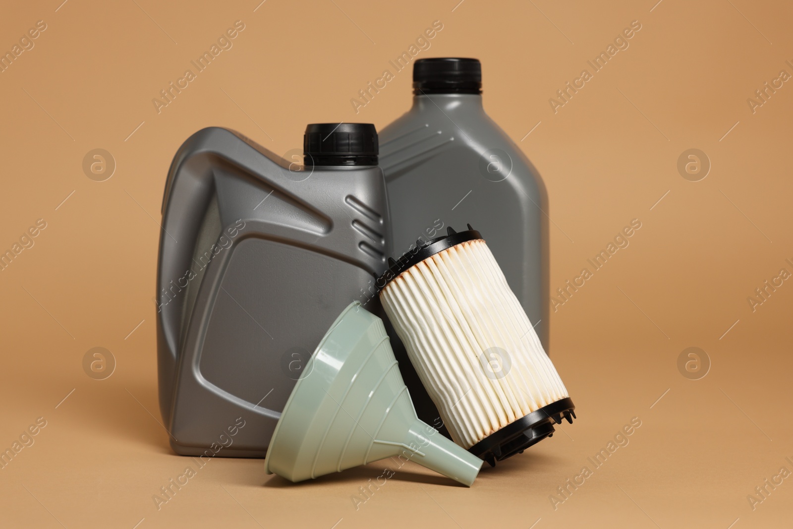 Motor oil in plastic canisters, filter and funnel on beige background Photo of Motor oil in plastic canisters, filter and funnel on beige background