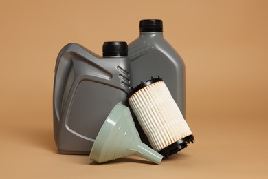 Photo of Motor oil in plastic canisters, filter and funnel on beige background