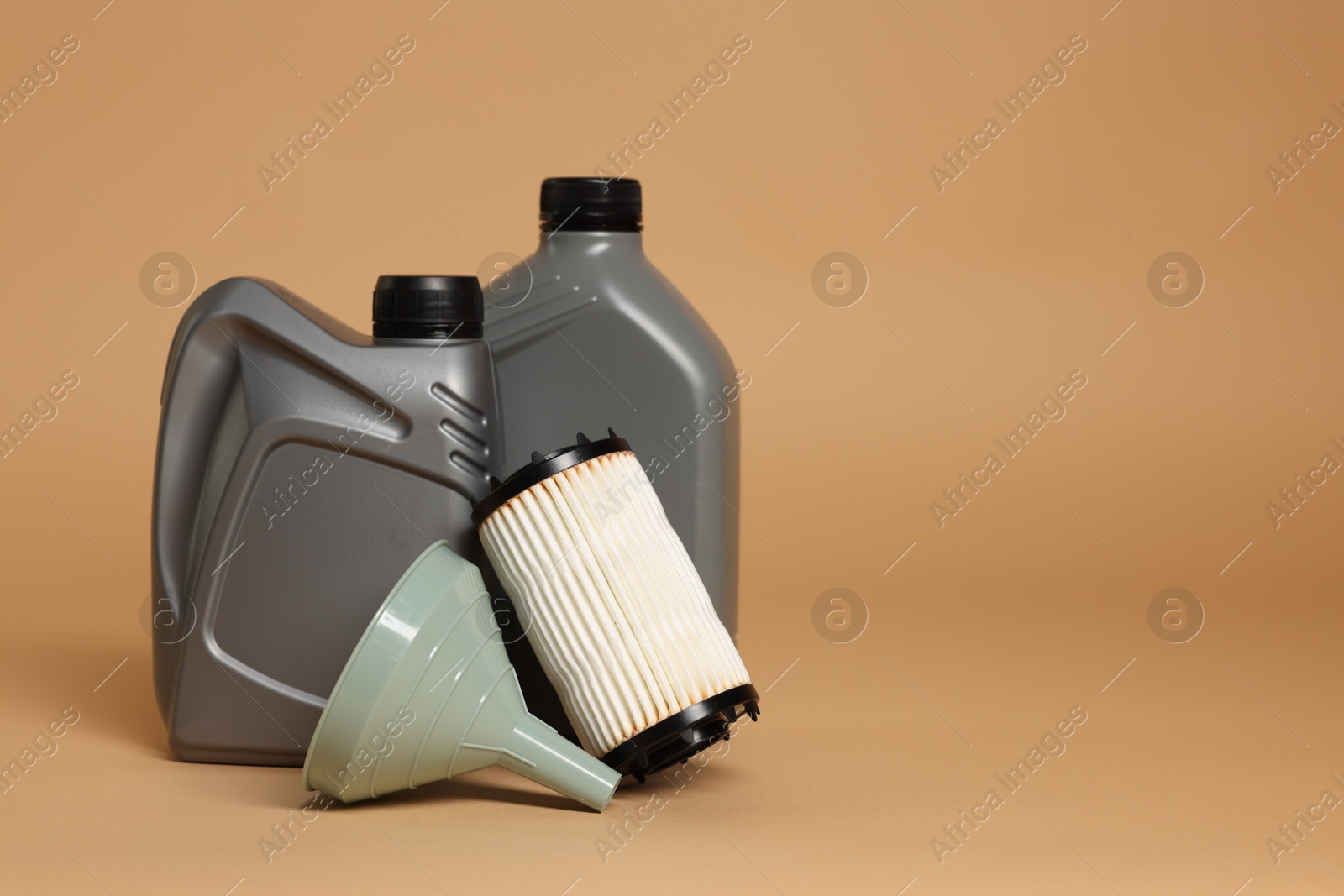 Motor oil in plastic canisters, filter and funnel on beige background, space for text Photo of Motor oil in plastic canisters, filter and funnel on beige background, space for text
