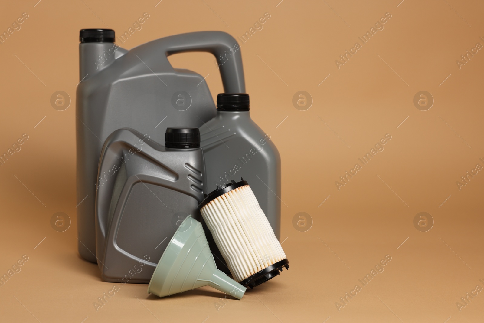 Motor oil in plastic canisters, filter and funnel on beige background, space for text Photo of Motor oil in plastic canisters, filter and funnel on beige background, space for text