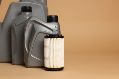 Photo of Motor oil in plastic canisters and filter on beige background, closeup. Space for text