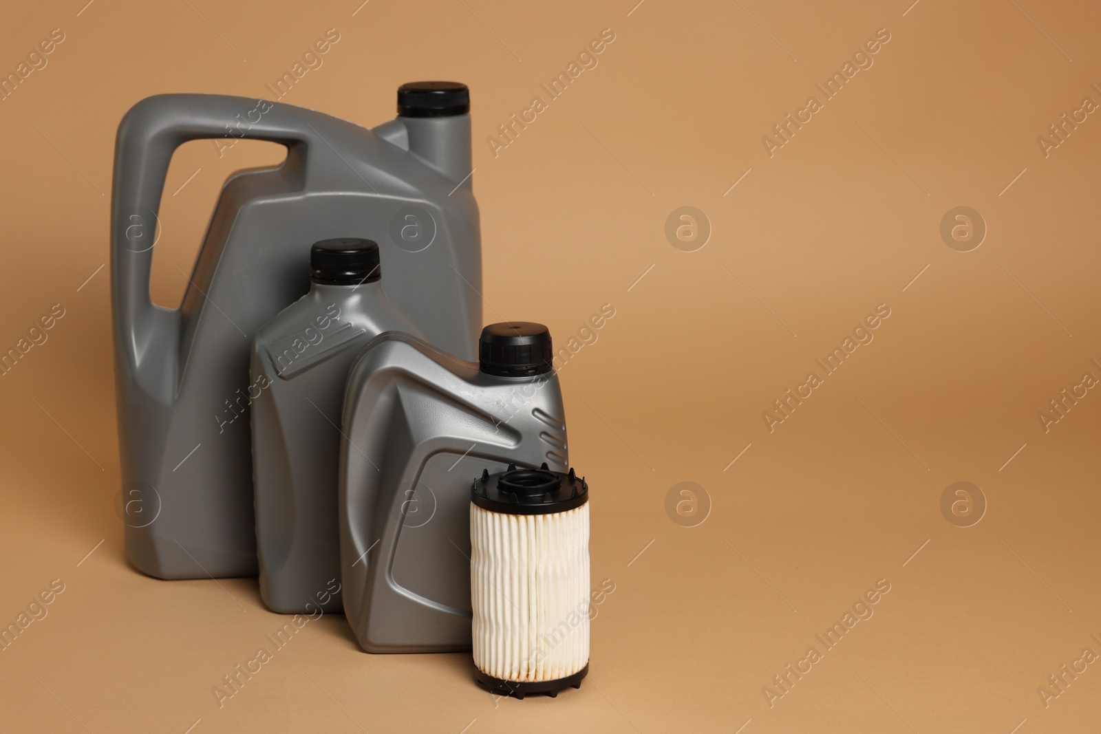 Motor oil in plastic canisters and filter on beige background, space for text Photo of Motor oil in plastic canisters and filter on beige background, space for text