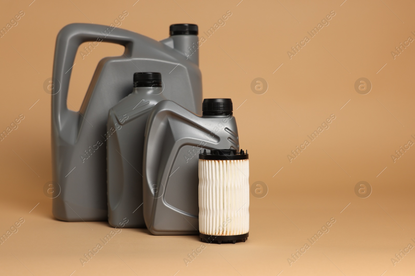 Motor oil in plastic canisters and filter on beige background, space for text Photo of Motor oil in plastic canisters and filter on beige background, space for text