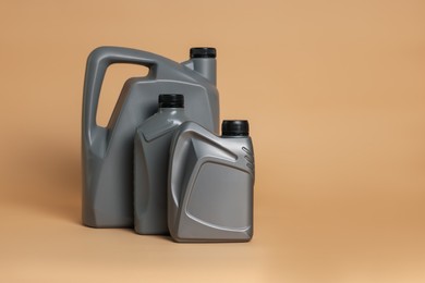 Photo of Motor oil in plastic canisters on beige background, space for text