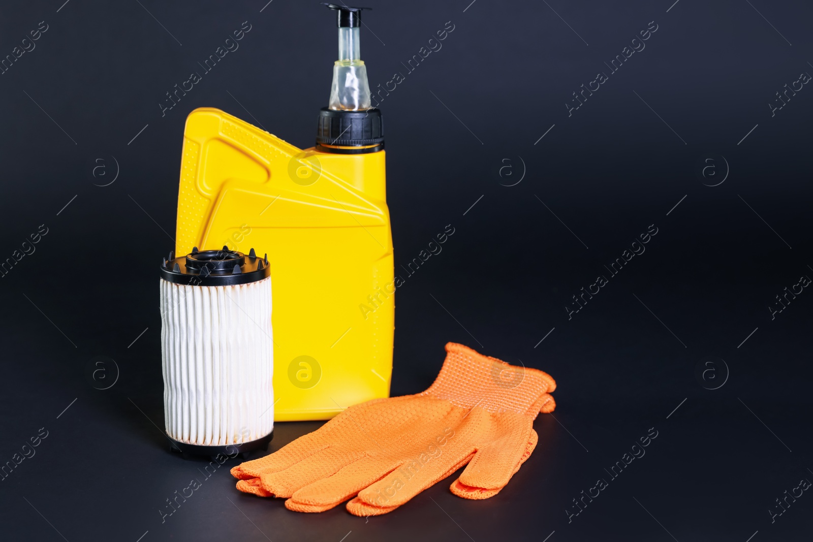 Motor oil in plastic canister, gloves and filter on dark grey background, space for text Photo of Motor oil in plastic canister, gloves and filter on dark grey background, space for text
