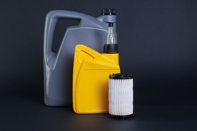 Photo of Motor oil in plastic canisters and filter on dark grey background