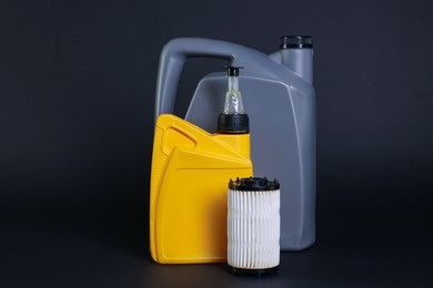 Photo of Motor oil in plastic canisters and filter on dark grey background
