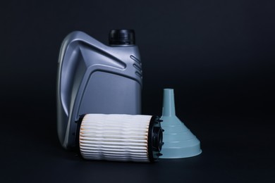 Photo of Motor oil in plastic canister, filter and funnel on dark grey background