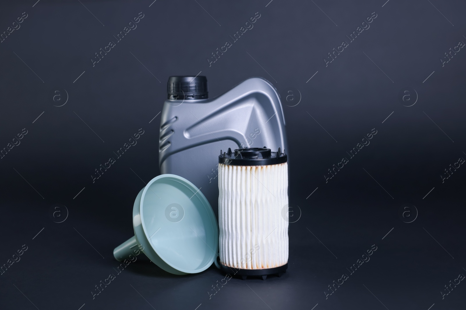 Motor oil in plastic canister, filter and funnel on dark grey background Photo of Motor oil in plastic canister, filter and funnel on dark grey background