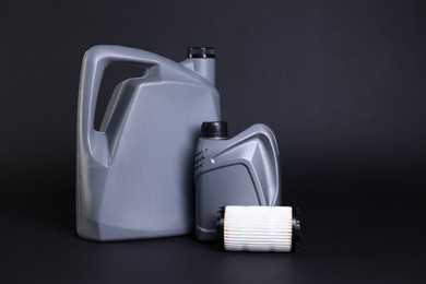 Photo of Motor oil in plastic canisters and filter on black background, space for text