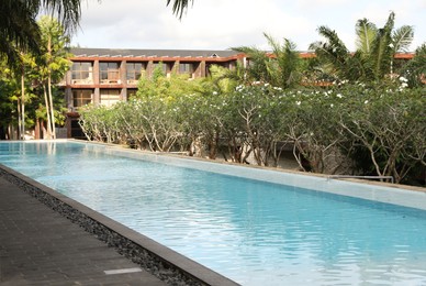 Photo of Outdoor swimming pool, building and green plants at luxury resort
