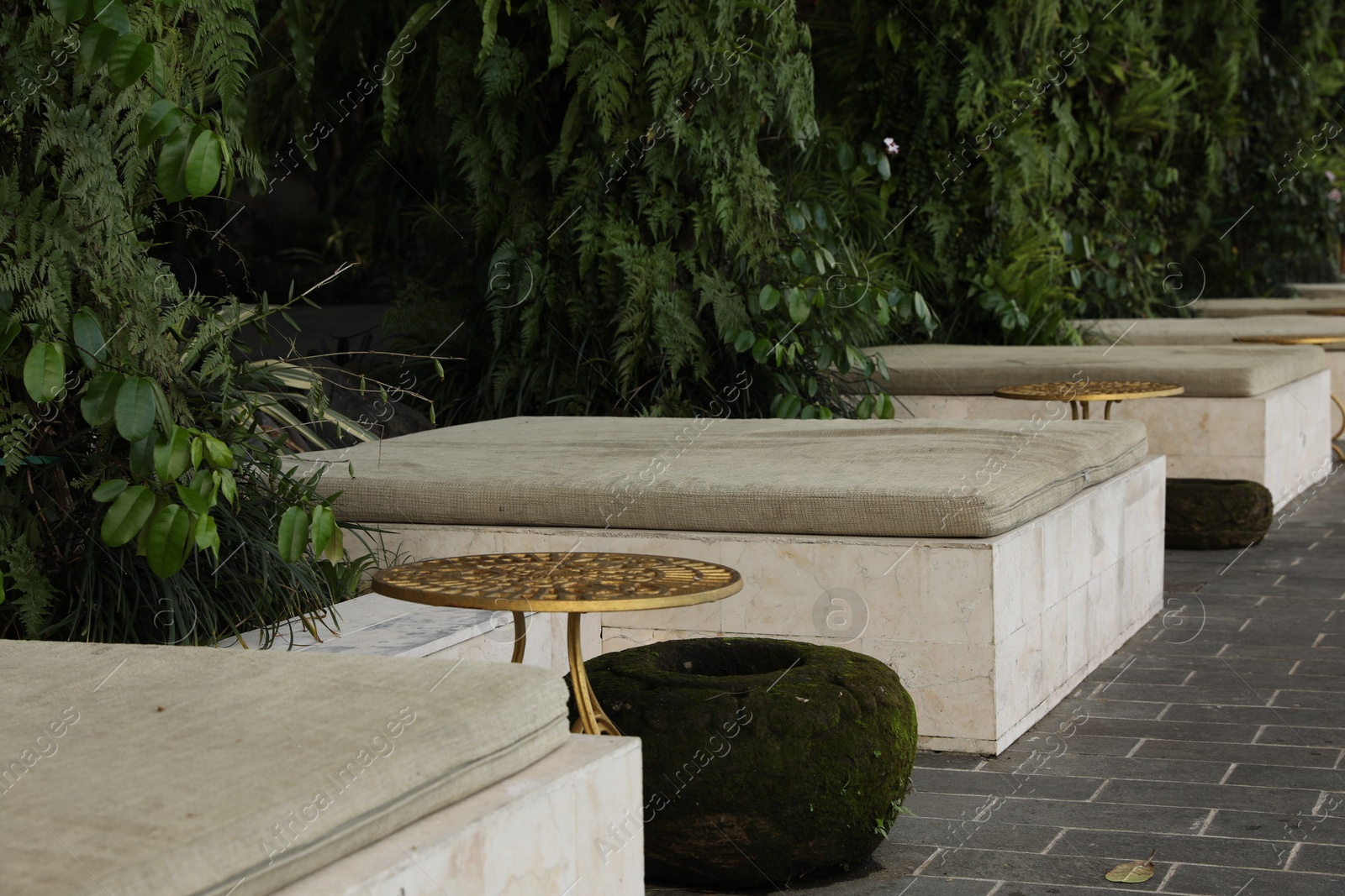 Tables, lounge seats, planter and green plants in park Photo of Tables, lounge seats, planter and green plants in park