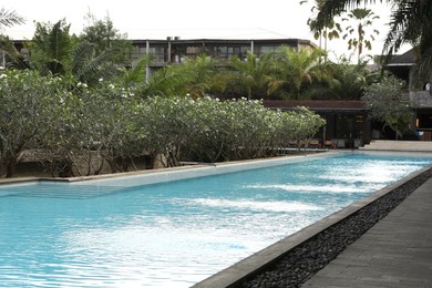Photo of Outdoor swimming pool, building and green plants at luxury resort