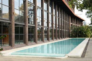 Photo of Outdoor swimming pool and green plants near building at luxury resort