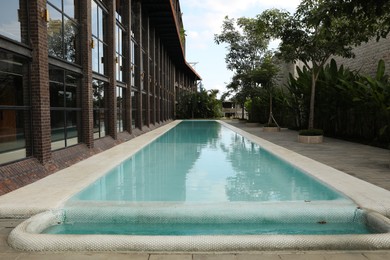 Photo of Outdoor swimming pool and green plants near building at luxury resort