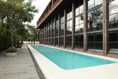 Photo of Outdoor swimming pool and green plants near building at luxury resort