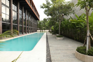 Photo of Outdoor swimming pool and green plants near building at luxury resort