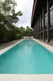 Photo of Outdoor swimming pool and green plants near building at luxury resort