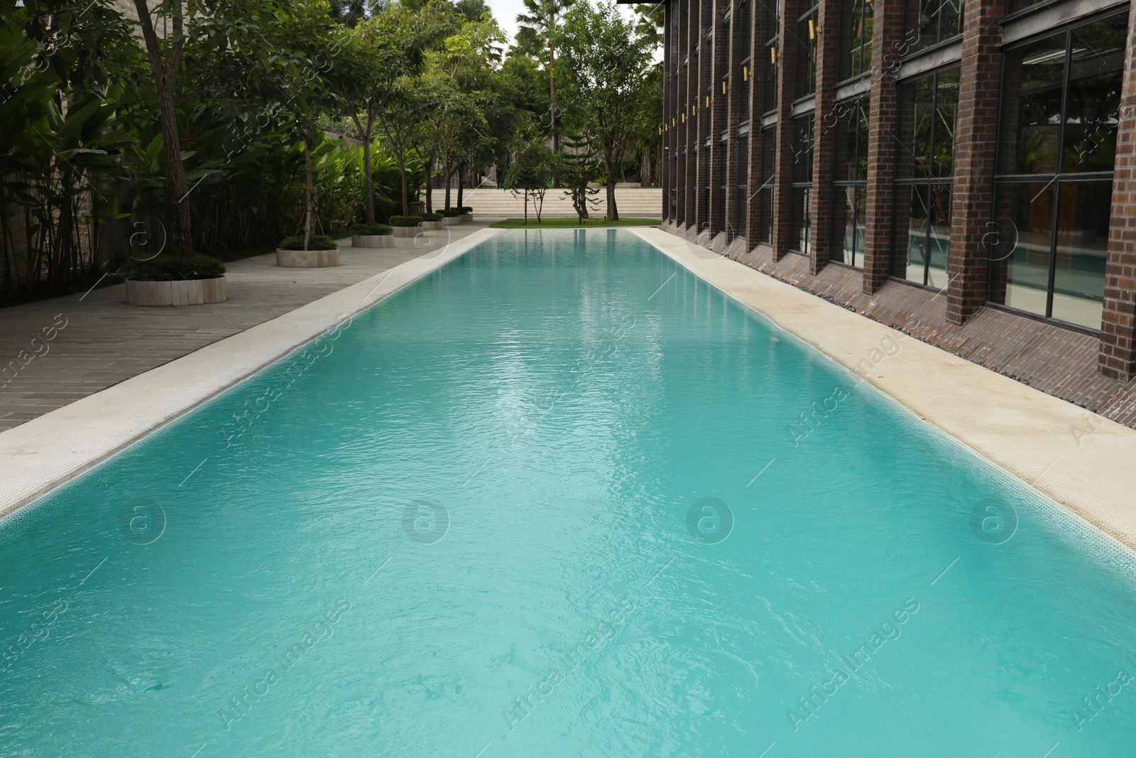 Outdoor swimming pool and green plants near building at luxury resort Photo of Outdoor swimming pool and green plants near building at luxury resort