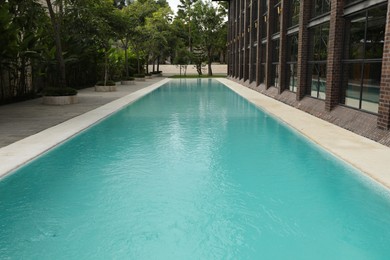 Photo of Outdoor swimming pool and green plants near building at luxury resort