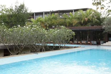 Photo of Outdoor swimming pool and green plants near building at luxury resort