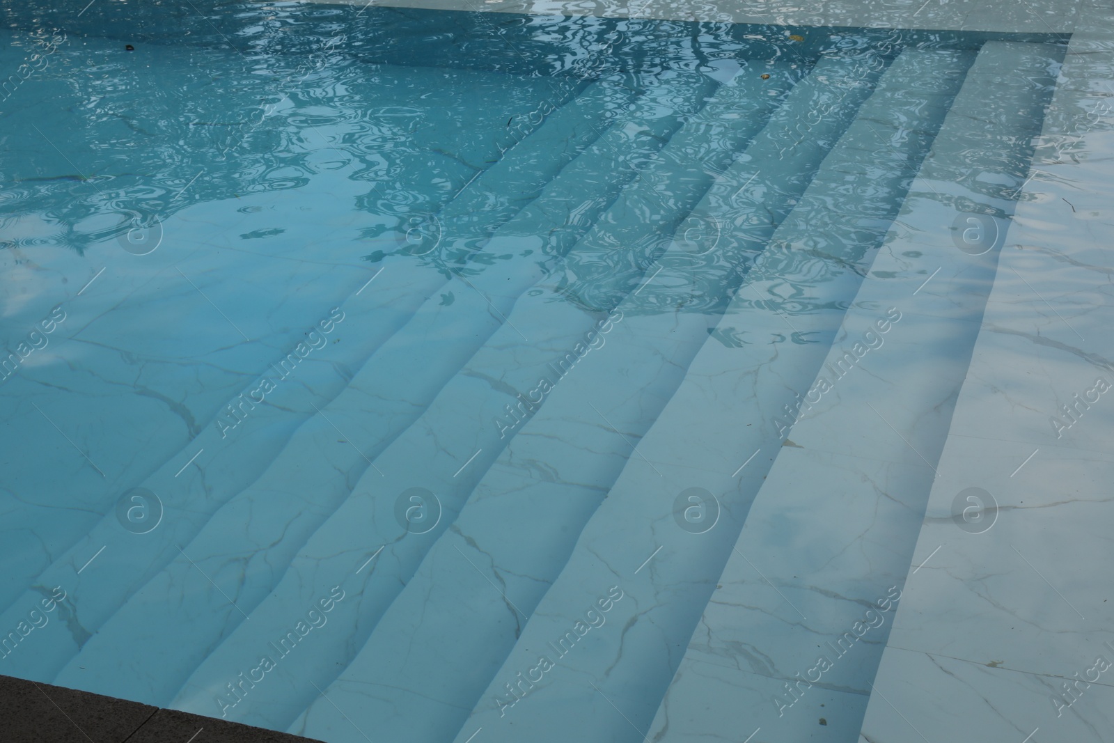 Clear water with ripples and stairs in outdoor swimming pool, closeup Photo of Clear water with ripples and stairs in outdoor swimming pool, closeup