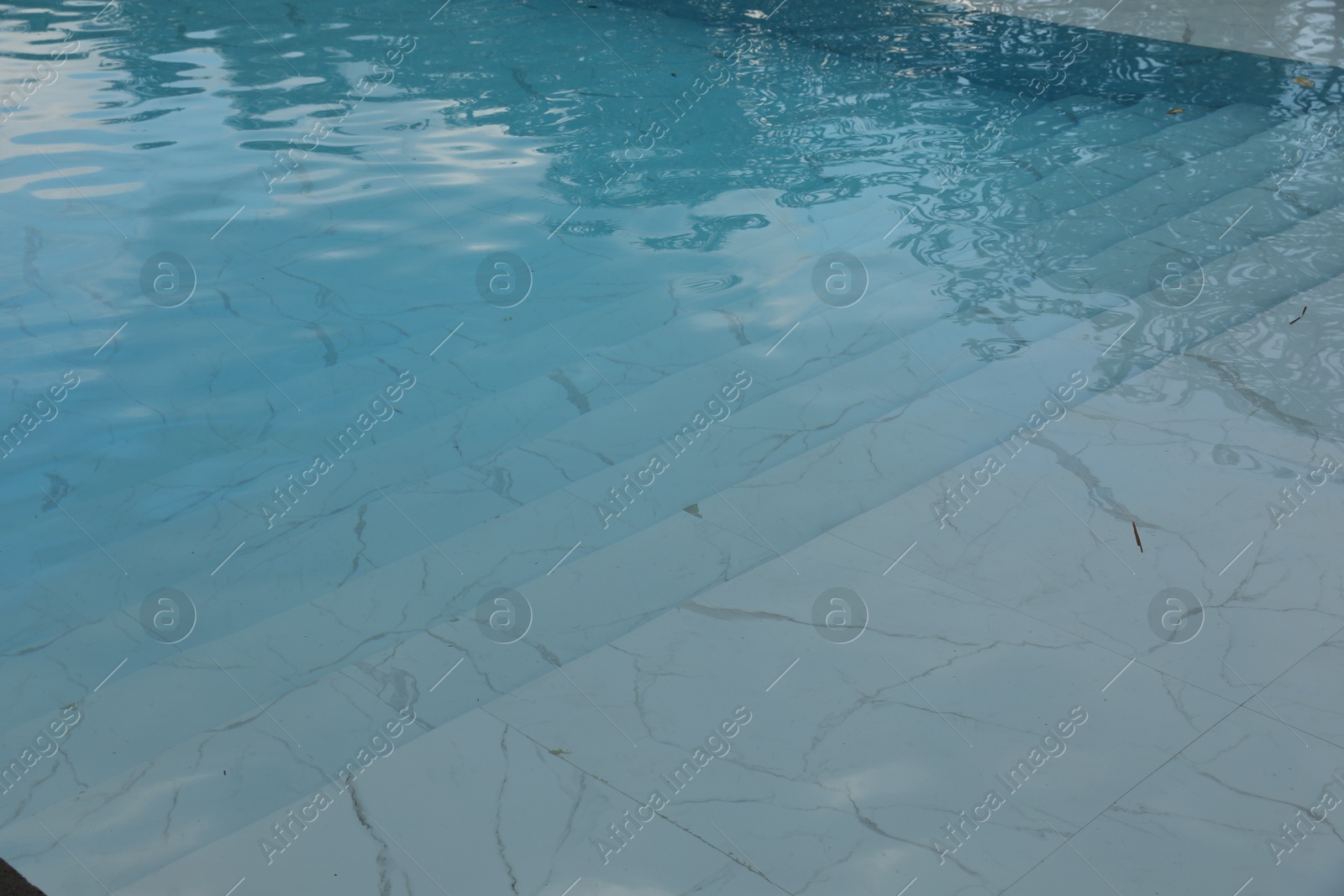 Clear water with ripples and stairs in outdoor swimming pool, closeup Photo of Clear water with ripples and stairs in outdoor swimming pool, closeup
