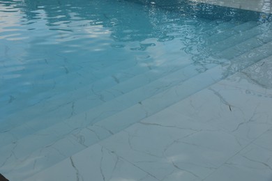 Photo of Clear water with ripples and stairs in outdoor swimming pool, closeup