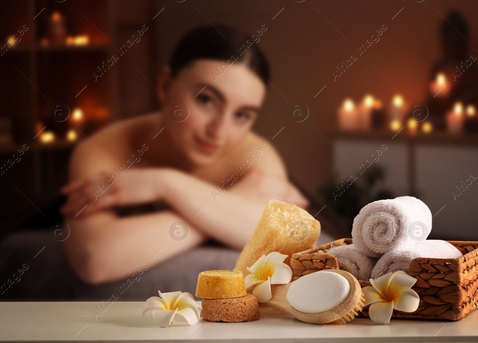 Spa therapy. Woman lying on massage table and different body care products in salon, selective focus Image of Spa therapy. Woman lying on massage table and different body care products in salon, selective focus